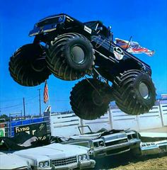 a monster truck is in the air over cars