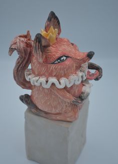 a ceramic sculpture of a dog with a crown on its head and teeth in his mouth