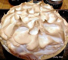 a pie sitting on top of a pan covered in frosting next to two jars