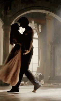 a man and woman are dancing in an old fashion dance studio with their arms around each other