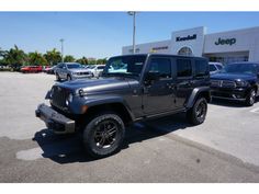 a gray jeep parked in front of a jeep dealership with other cars behind it