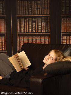 a woman laying on a couch reading a book