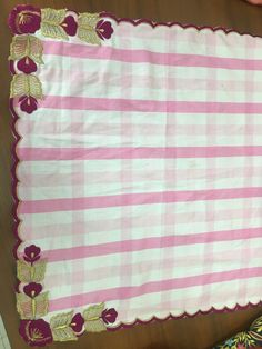 a pink and white checkered table cloth with gold trimmings on the edge