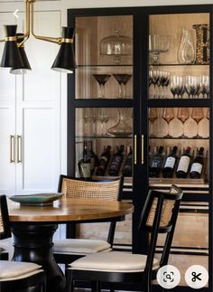 a dining room table and chairs with wine glasses on the shelves in front of them