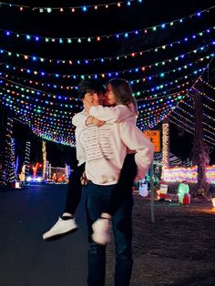 a man and woman hugging in front of christmas lights