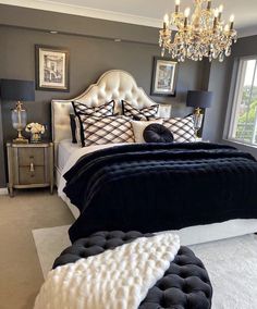 a bedroom with a chandelier and black and white bedding, rugs on the floor