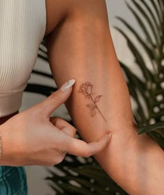 a woman's arm with a small flower tattoo on the left side of her arm