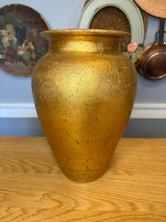 a gold vase sitting on top of a wooden table