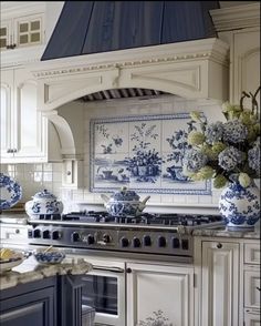 a kitchen with blue and white decor on the wall, stove top and oven hood