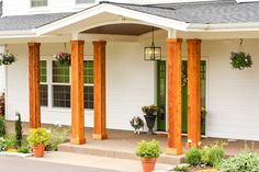 a white house with wooden pillars and flower pots