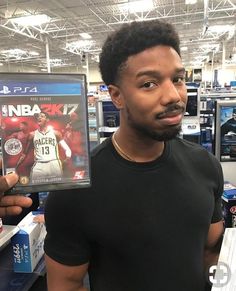 a man holding up a video game in front of his face while standing in a store