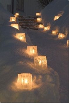 lighted candles are lined up in the snow to be used as walkways or steps