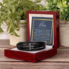 a wooden box with a cross on it next to some potted plants and a plaque