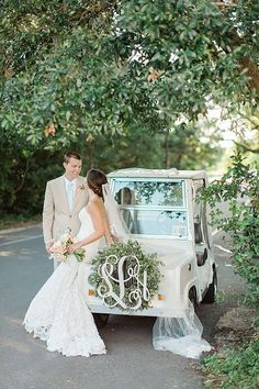 a bride and groom standing in front of an old car with the initials on it