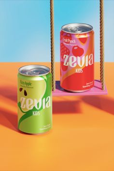 two cans of soda sitting on top of an orange floor next to a swing set