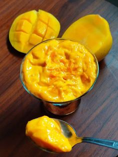 a spoon with some food in it on top of a wooden table next to sliced mangoes