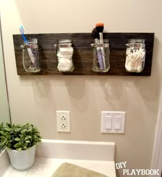 three mason jars are hanging on the wall above a toilet