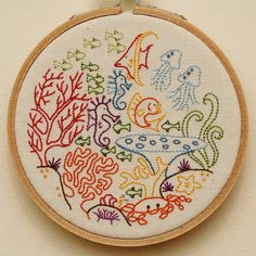 an embroidered hoop hanging on the wall with some embroidery work in it's center