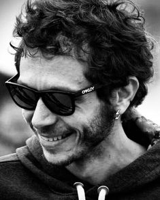 a man with curly hair and sunglasses smiling