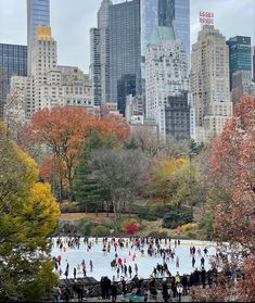 many people are skating on an ice rink in central park, with skyscrapers in the background