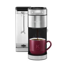 a red coffee cup sitting next to a silver and black coffee maker