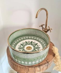 a bowl shaped sink sitting on top of a wooden stand next to a faucet