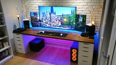 a desk with a computer on it in front of a brick wall and wooden floor