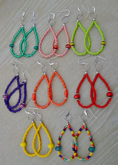 six pairs of beaded earrings are shown in different colors and sizes on a table