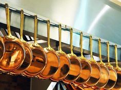 copper colored pots and pans hanging from a rack in a restaurant or kitchen area