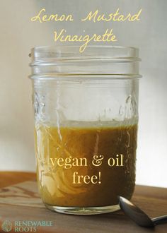 a jar filled with vegan and oil on top of a wooden table next to a spoon