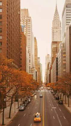 an empty city street with tall buildings and cars driving down the road in front of them