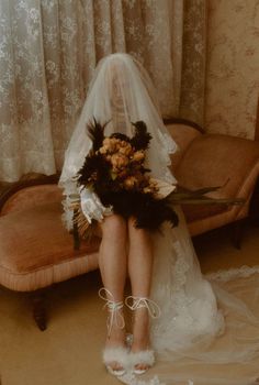 a bride sitting on a couch with her wedding bouquet