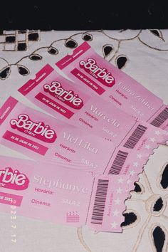 three pink tickets sitting on top of a white tablecloth covered in black and white designs