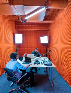 two men sitting at a table in an orange room