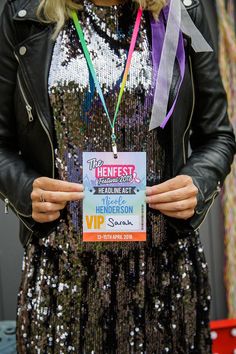 a woman in a sequin dress holding up a sign with ribbons around her neck