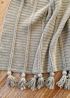 a knitted blanket with tassels laying on the floor