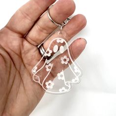 a hand holding a clear plastic angel keychain with white flowers and hearts on it