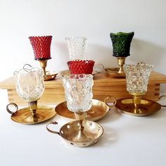 four glass candlesticks sitting on top of gold plated dishes and trays