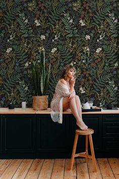 a woman sitting on top of a stool next to a counter