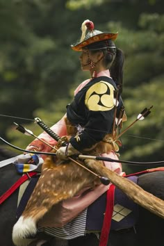 a woman riding on the back of a horse with an arrow in her hand and wearing a hat