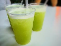 two glasses filled with green liquid sitting on top of a table