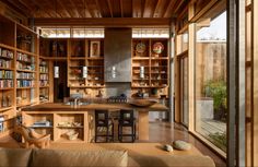 a living room filled with lots of furniture and bookshelves next to a kitchen