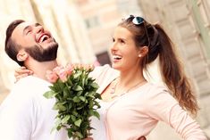 a man holding a bouquet of flowers next to a smiling woman with her arms around him