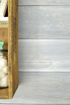 an open wooden box with cotton in it on a white wood wall next to a pair of scissors