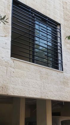 an open window on the side of a building with black shutters and metal bars