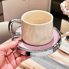 a person holding a coffee cup and saucer