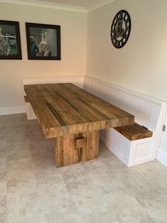 a wooden table and bench in a room with two pictures on the wall behind it