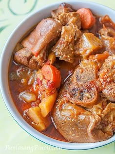 a close up of a bowl of food with meat and vegetables in it on a table