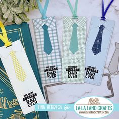 four bookmarks with ties on them sitting next to a plant and some other items