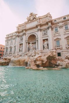 an ornate building with statues on the front and water running through it, near a fountain